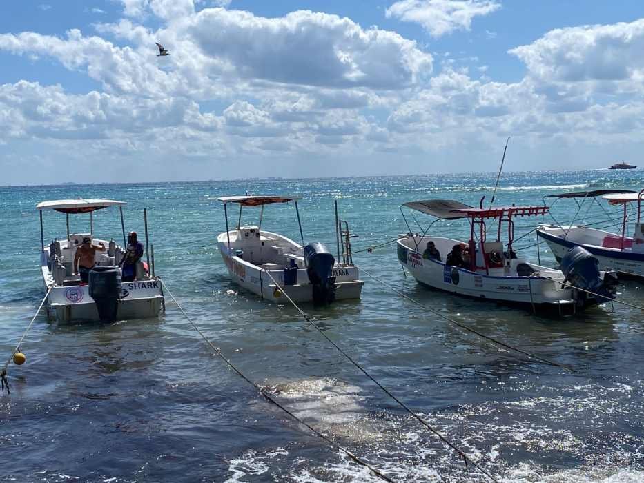 A tour boat dock in Playa del Carmen, Mexico, with boats moored along a pier.