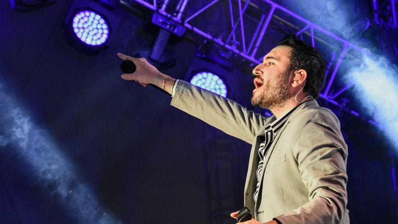 Reik performing live at a concert, with the Chetumal carnival logo in the background