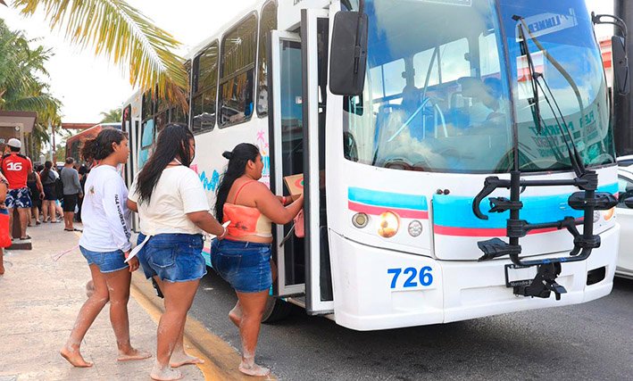 A white bus with the Ruta Mar logo parked near a beach in Cancún