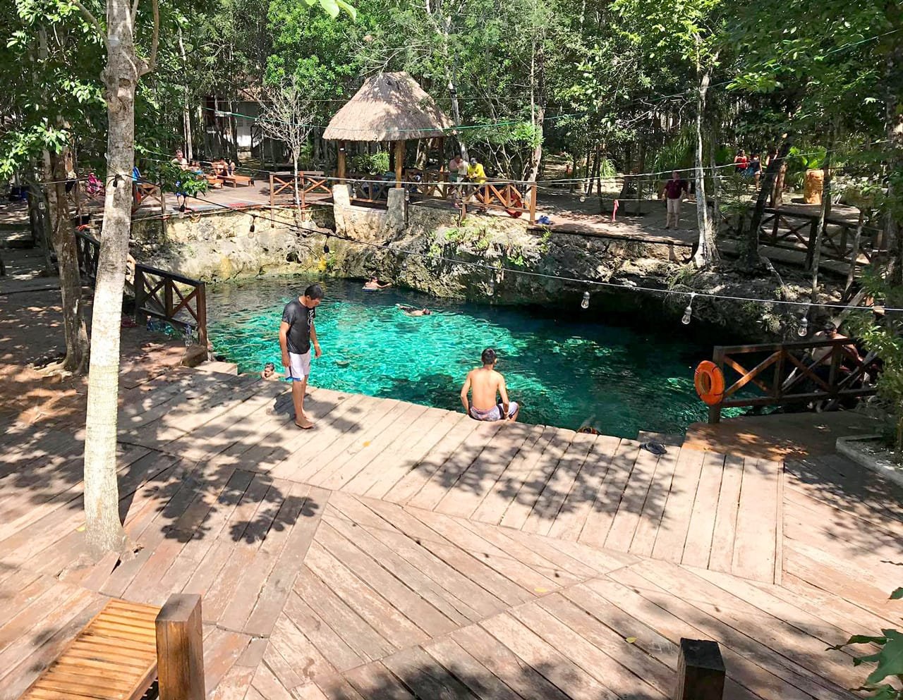 A scenic view of a cenote in Tulum, Mexico, showing clear turquoise water and rock formations