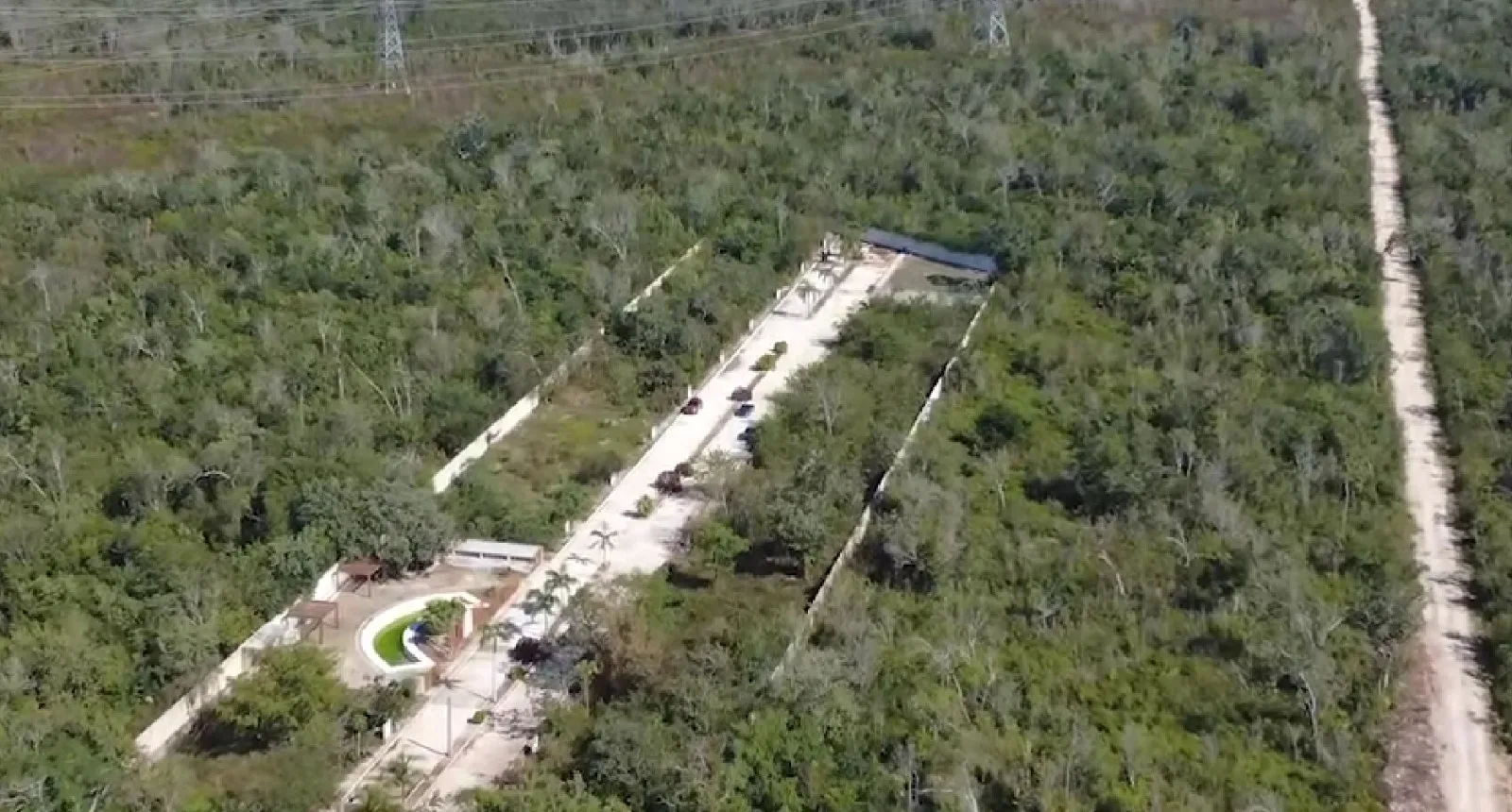 An aerial view of a densely wooded area with concrete roads and structures visible among the trees.$# CAPTION