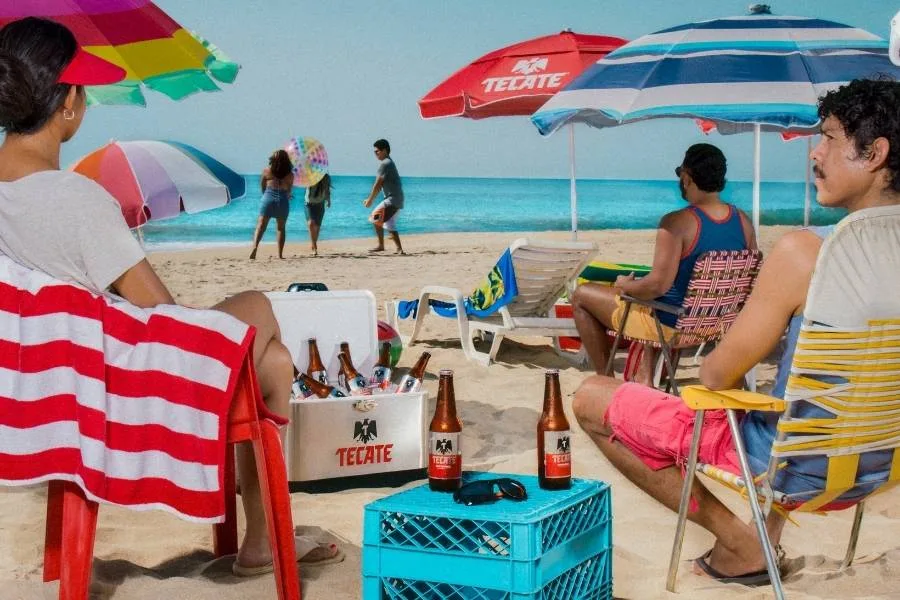 A public beach access point in Tulum, Mexico, with signage and recycling bins