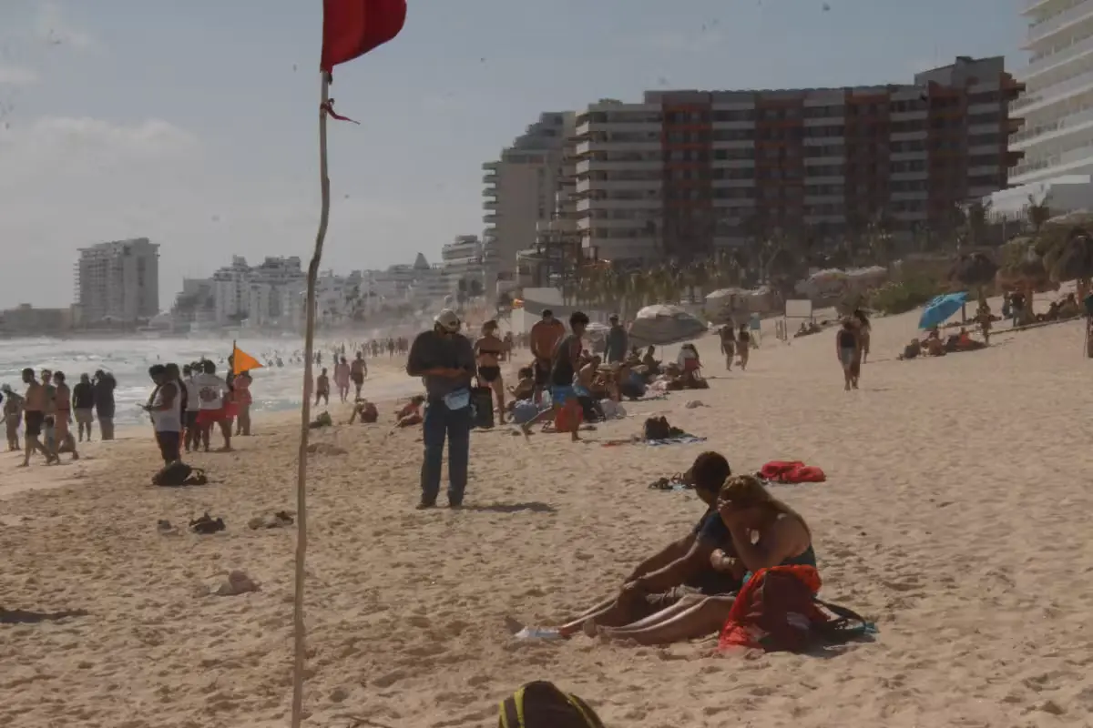 Red warning flags flying on a Cancún beach with rough ocean waves