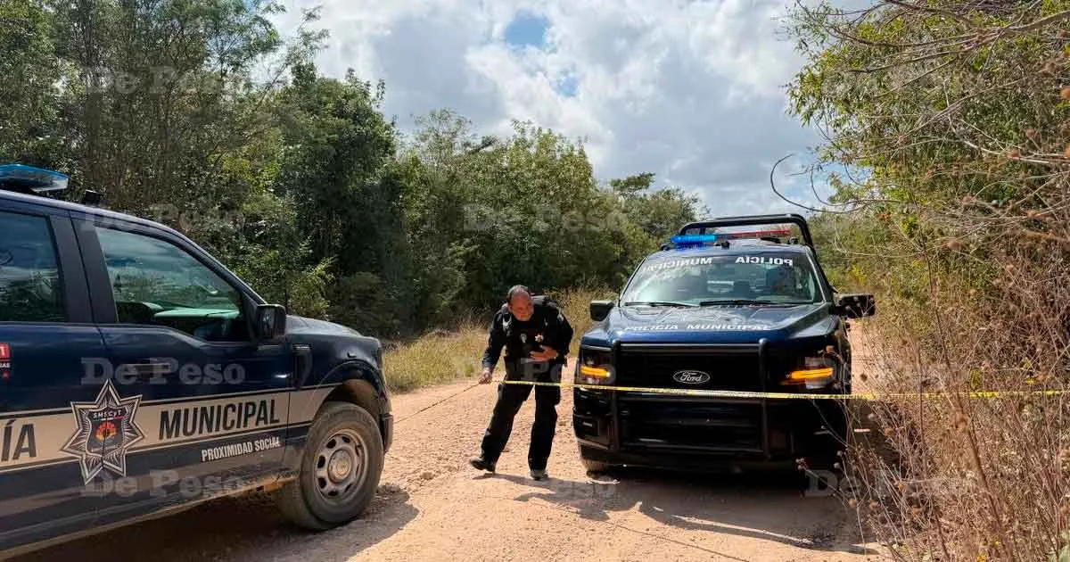 A dirt road in Cancun where a man was found dead, with police tape visible in the background