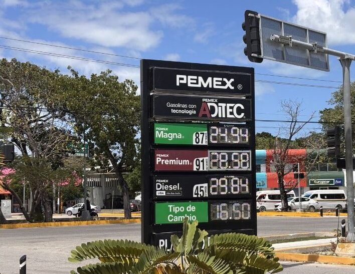 A gas station in Cancún displaying fuel prices, with regular gasoline priced above 24 pesos per liter