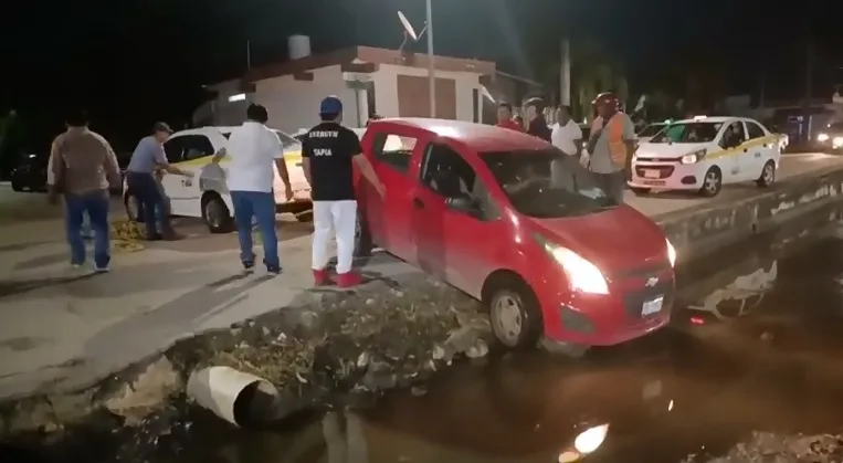 A car stuck in a storm drain at the intersection of Nicolás Bravo Avenue and Curacao Street in Chetumal's Caribe neighborhood