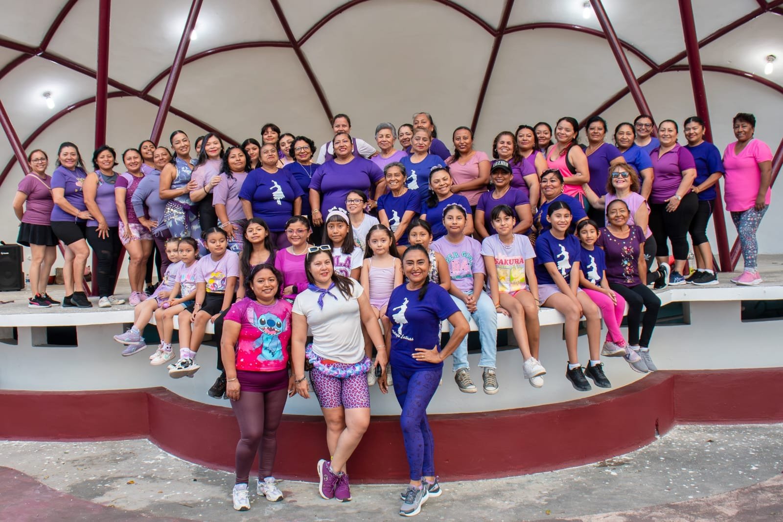 Women participating in a dance class at BiblioAvion Gervasio in Cozumel, wearing purple ribbons for International Women's Day