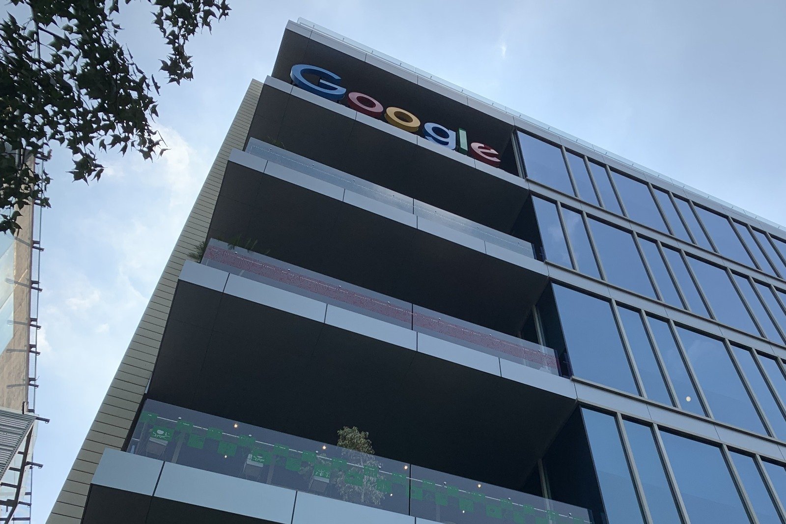 A view of the upper floors of a modern building with the Google logo displayed prominently at the top.$# CAPTION