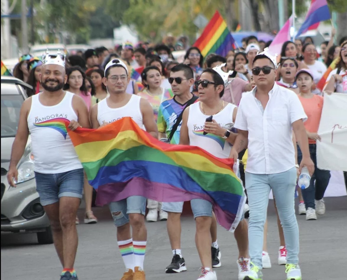 A group of LGBTQ+ activists holding signs during a protest in Quintana Roo, Mexico