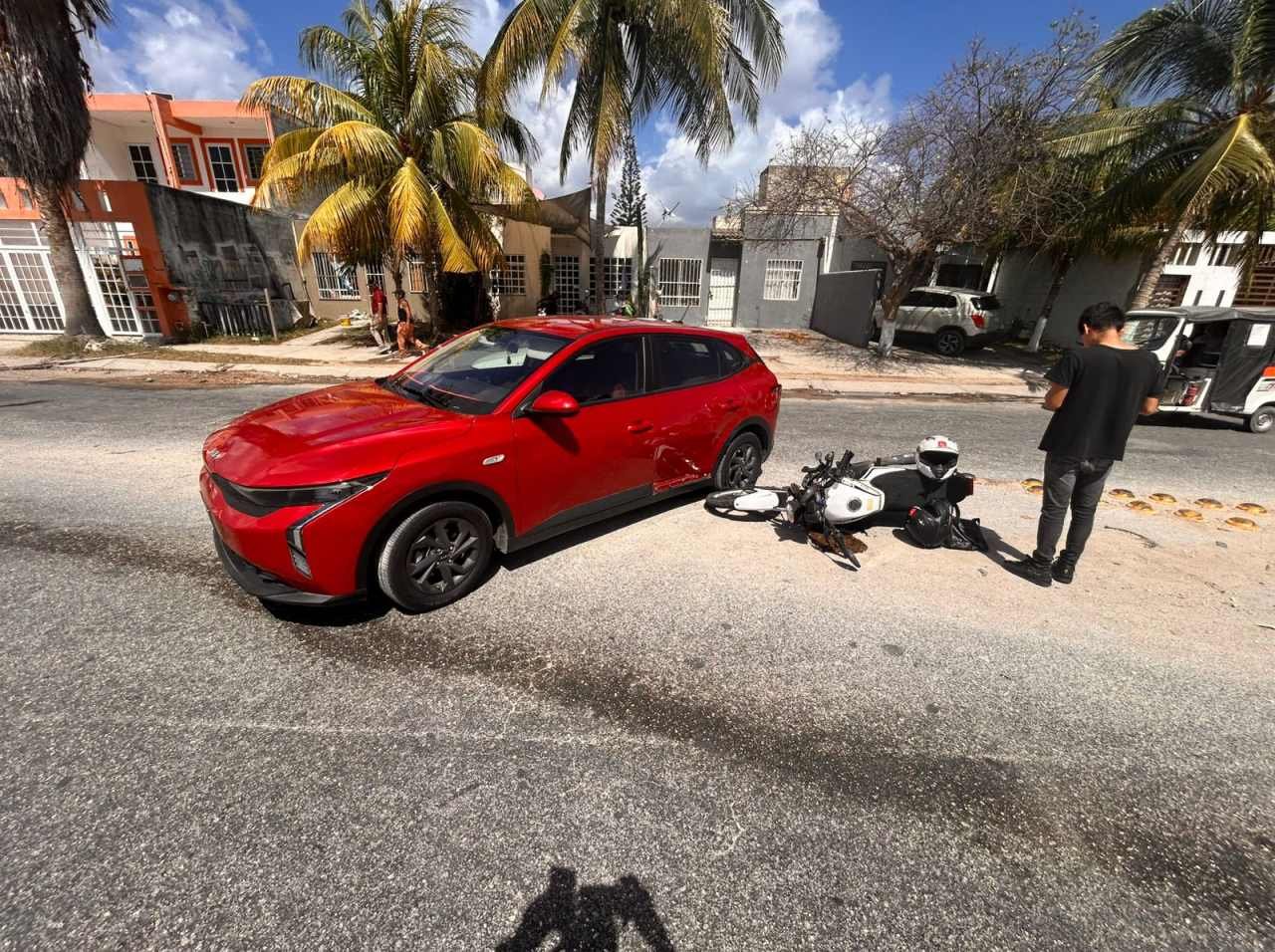 A red car and damaged motorcycle at the scene of a collision on Constituyentes Avenue in Playa del Carmen