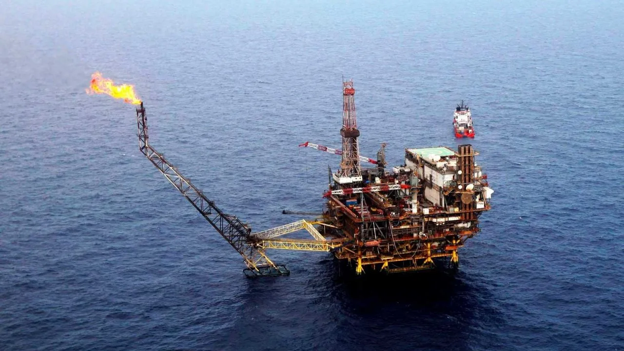 Oil barrels stacked at a Pemex facility with industrial equipment in the background