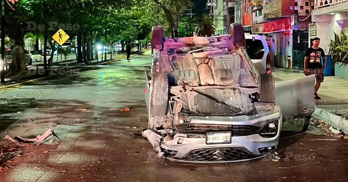 A gray Suzuki Baleno overturned on its roof after crashing into a tree in Playa del Carmen