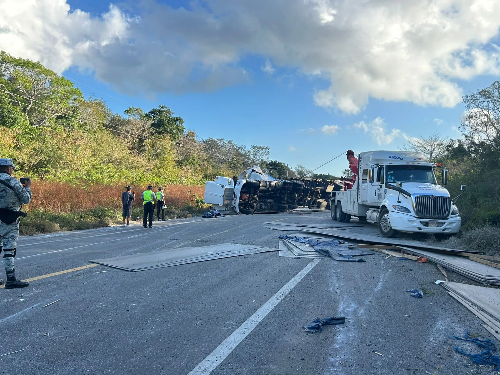 An overturned tractor-trailer on the Tulum-Felipe Carrillo Puerto highway, with metal sheets scattered on the road