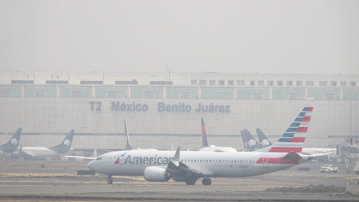 An airplane flies over a beach in Cancun, Mexico, as US airlines reduce flights to the destination.