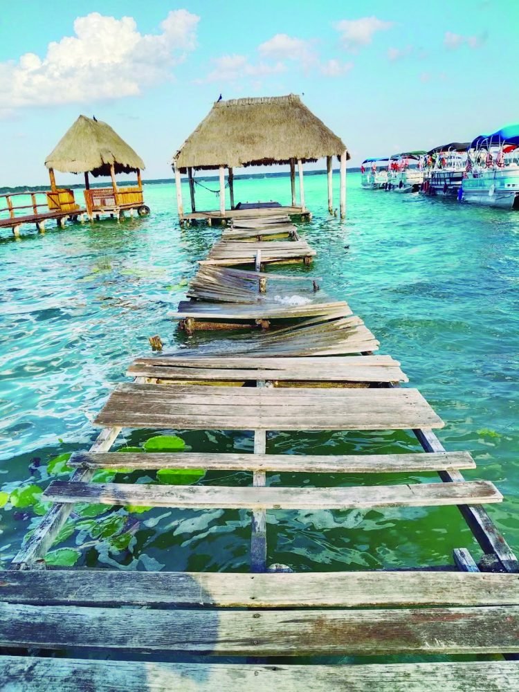 A decaying wooden pier in Bacalar, Quintana Roo, with visible rot and holes in the structure