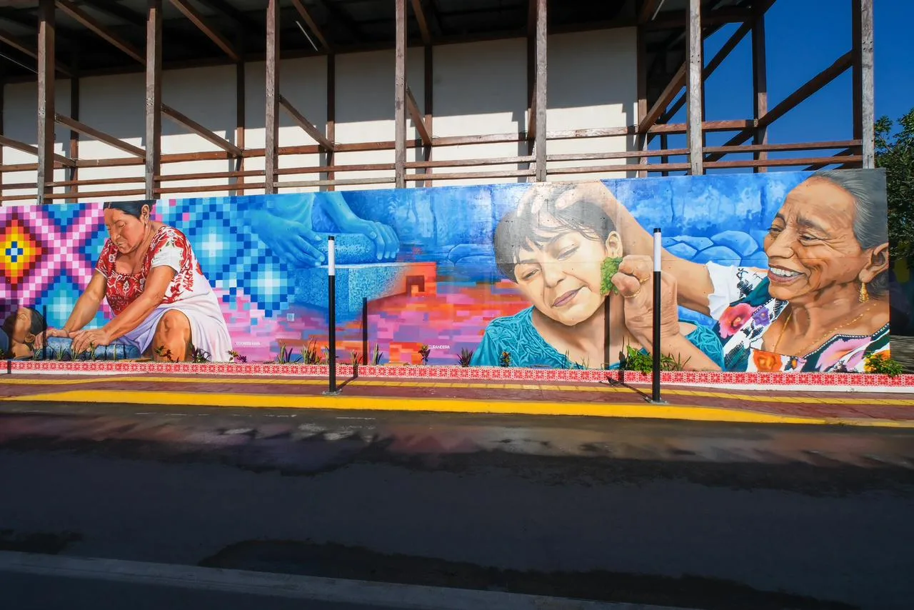 Officials and artists stand before a colorful mural during the inauguration of the Caminos Ancestrales cultural corridor in Felipe Carrillo Puerto.