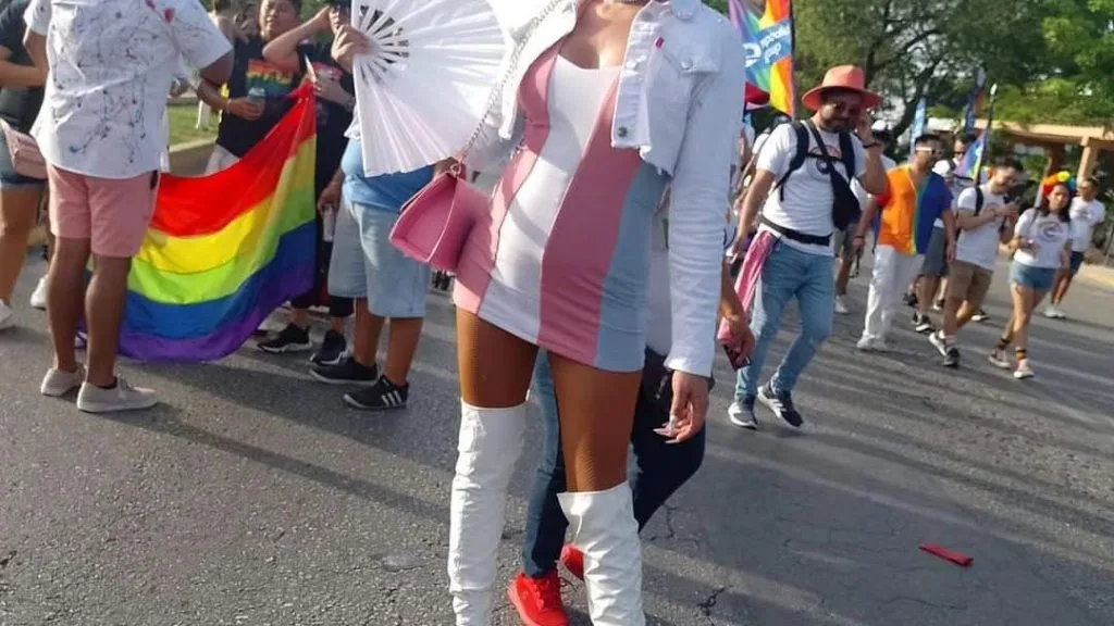 People marching in a Pride parade in Cancun with rainbow flags