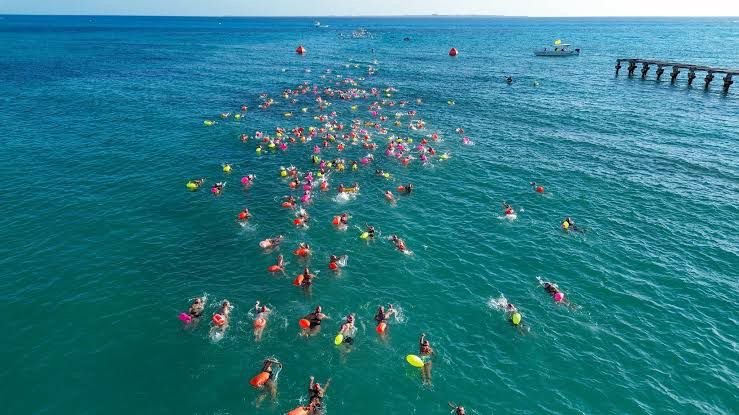 Swimmers participating in the Nado con causa event in the Caribbean Sea near Cancún