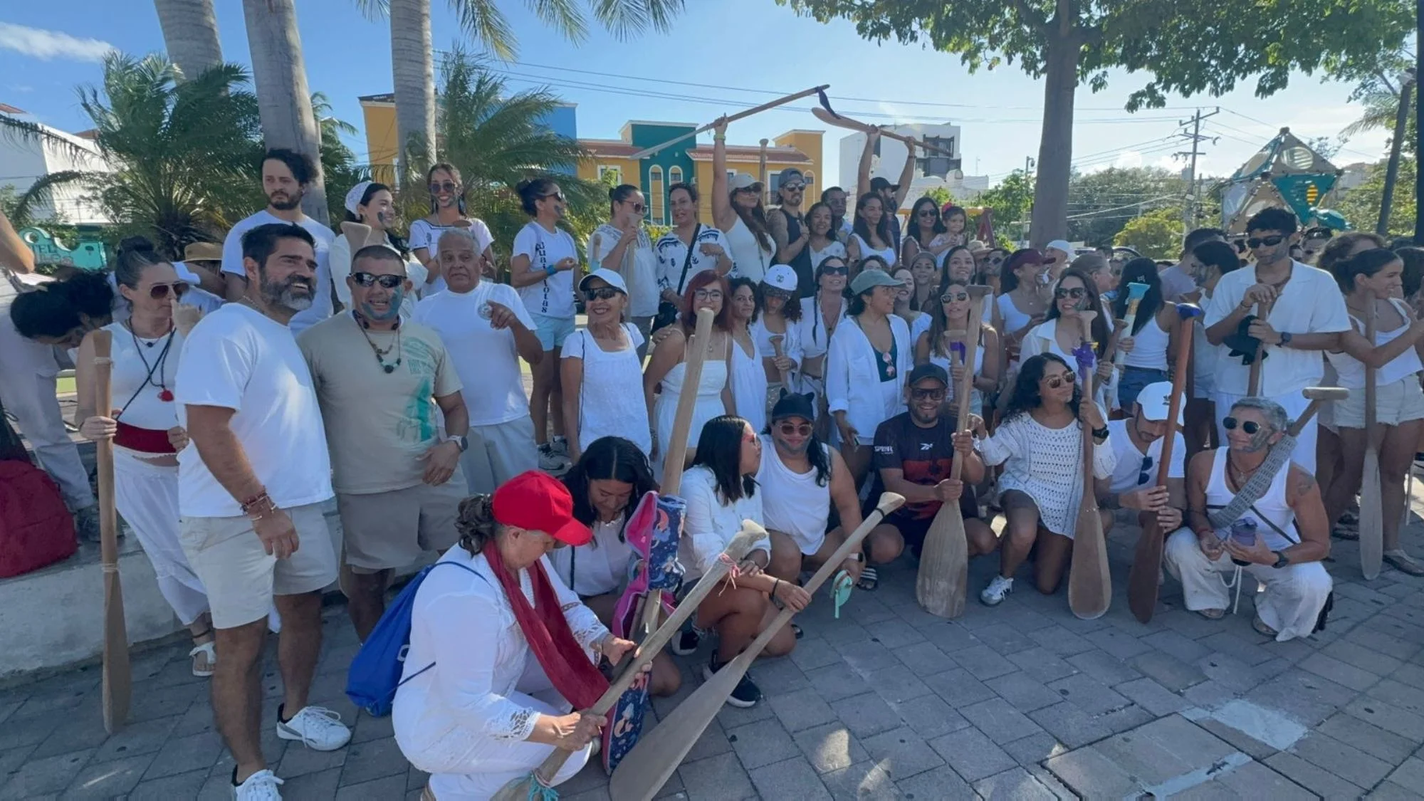 Canoers dressed in white holding paddles during a peaceful protest in Playa del Carmen