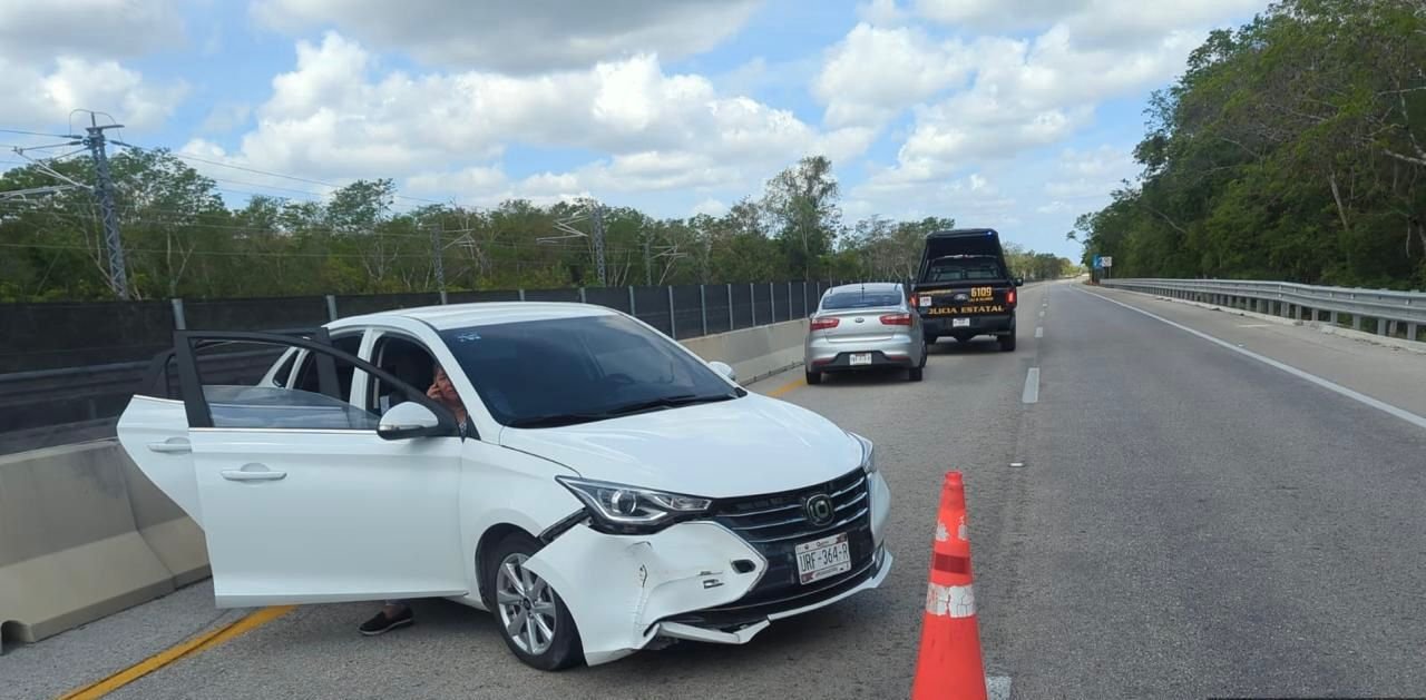 A white Changan car with front-end damage partially blocking a highway lane after a tire blowout accident near Kantunil, Yucatan