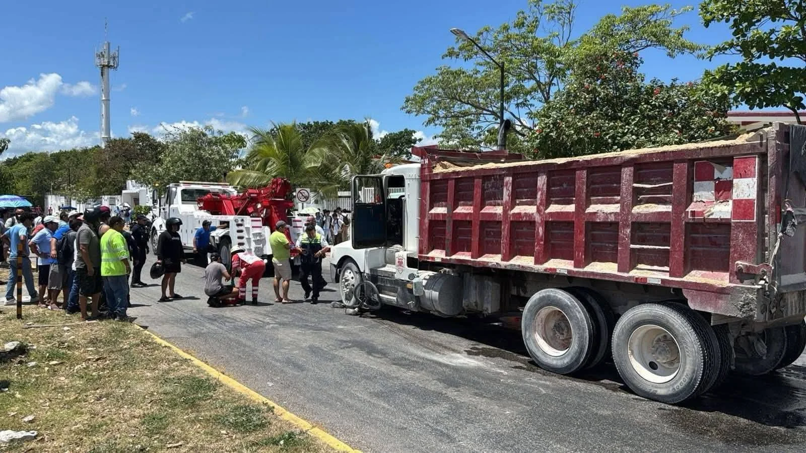 Emergency responders work to free a cyclist trapped under a dump truck at an intersection in Playa del Carmen