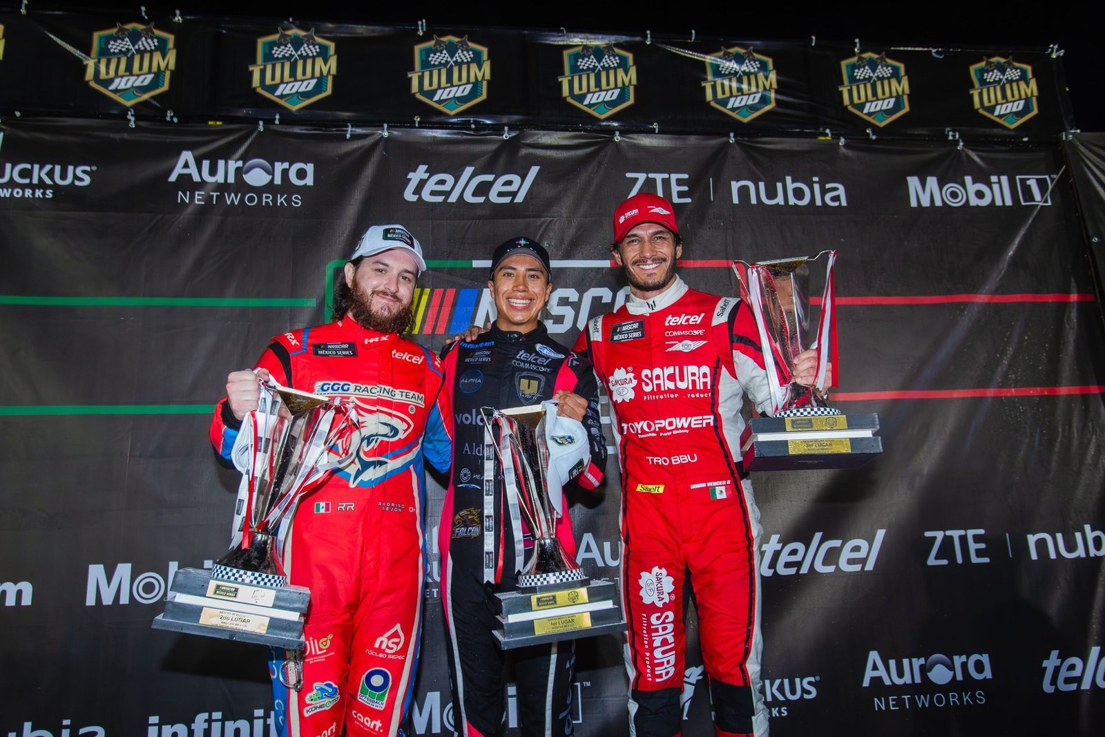 Eloy Sebastian Falcon holding trophy on podium at Tulum 100 NASCAR Mexico race