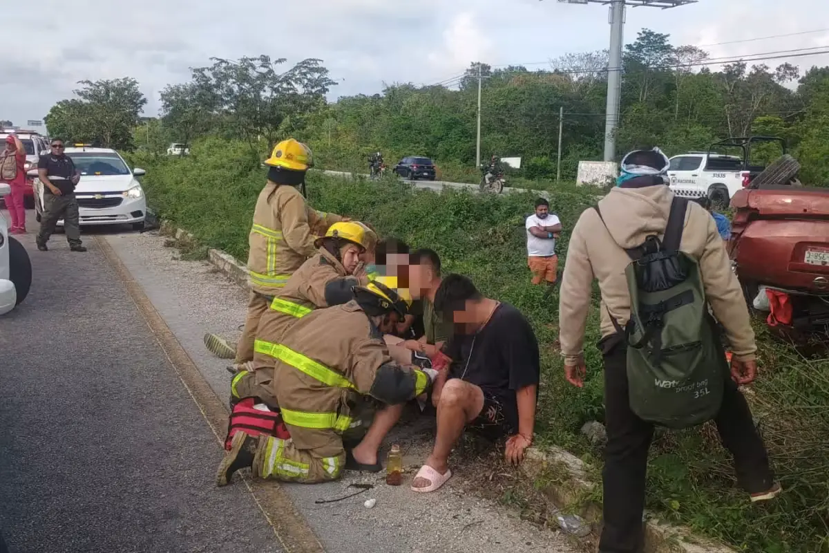 Firefighters and emergency personnel providing aid at the scene of a vehicle accident on a highway in Quintana Roo