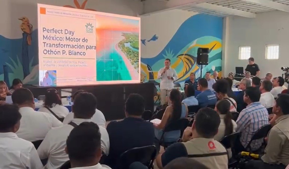 A presentation about the "Perfect Day México" initiative taking place in a community meeting with many attendees.$# CAPTION