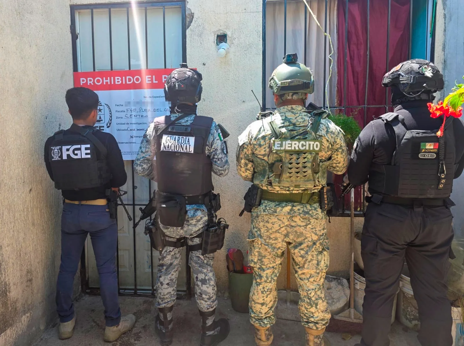 Police officers outside a house during a drug raid in Playa del Carmen