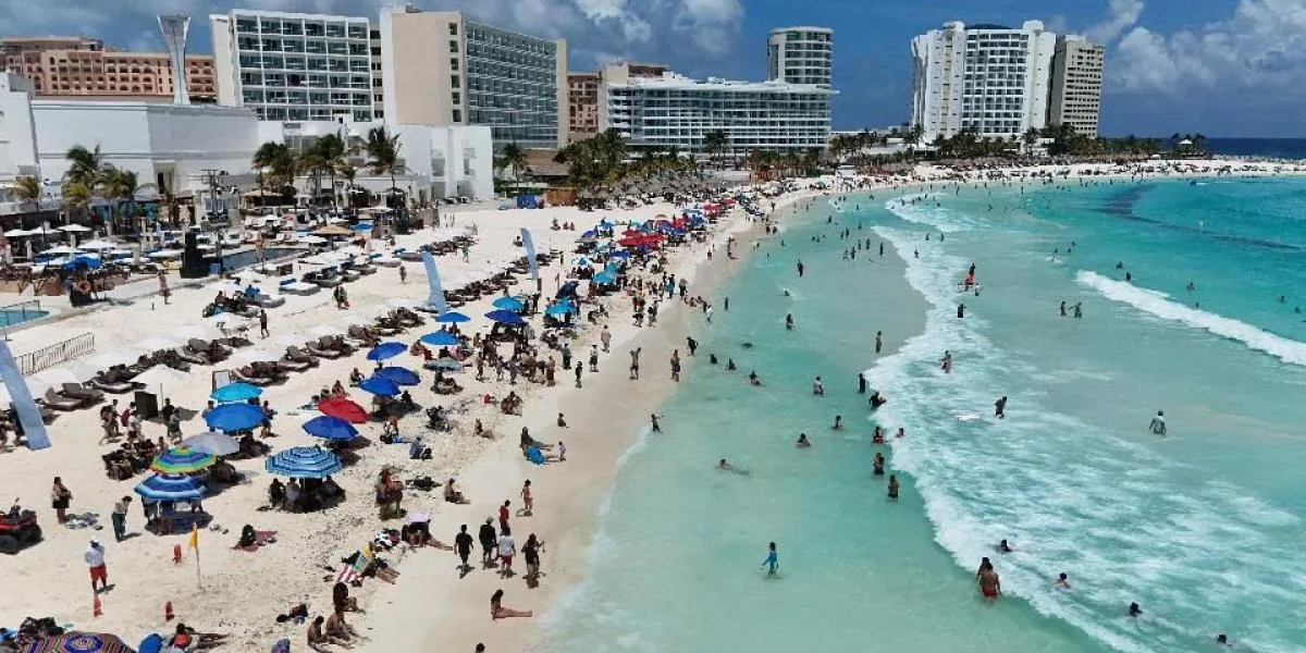 Tourists on a beach in Quintana Roo, Mexico, a key driver of the state's economic growth forecast for 2026.