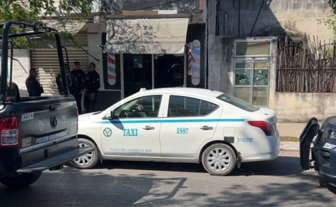 Police officers detain a taxi driver outside a cell phone store in Playa del Carmen