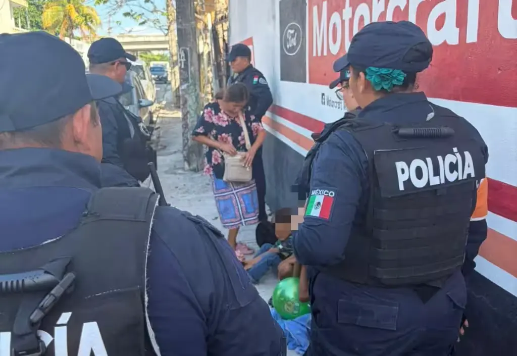 Three children sitting on a sidewalk under tree shade in Playa del Carmen