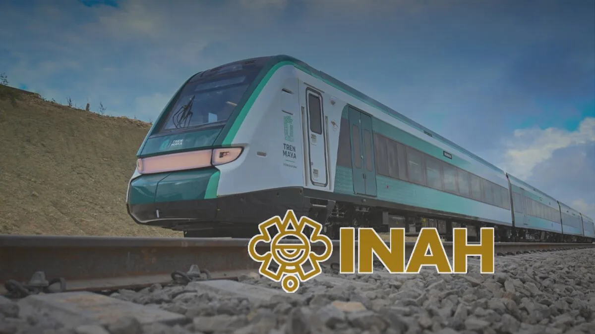 A modern Tren Maya train positioned on railway tracks with a blue sky in the background.