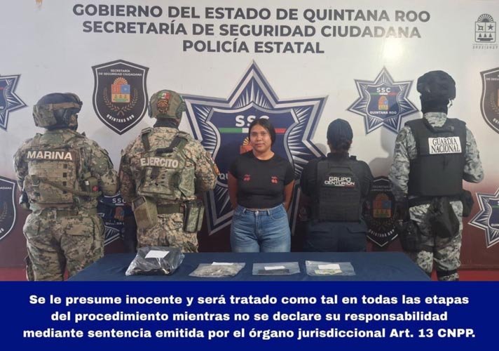 Police officers detain a woman on a street in Holbox, holding bags of suspected marijuana.