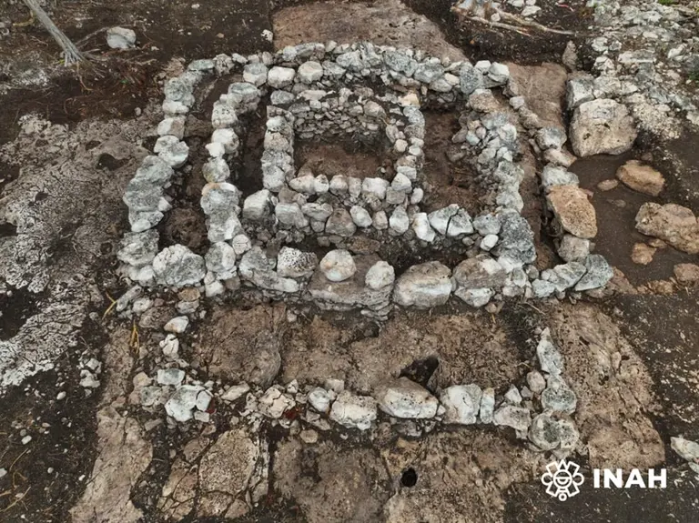 Archaeologists examining a quadrangular Maya stone structure with three levels and a carved cavity, found during Maya Train construction in Yucatan.