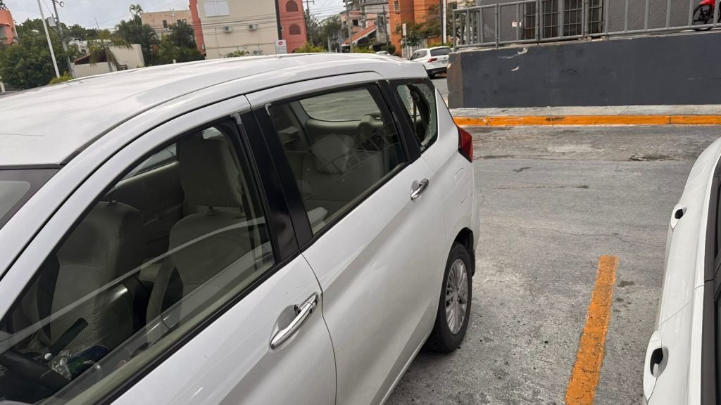 A vandalized SUV with a broken window in a parking lot in Cancun