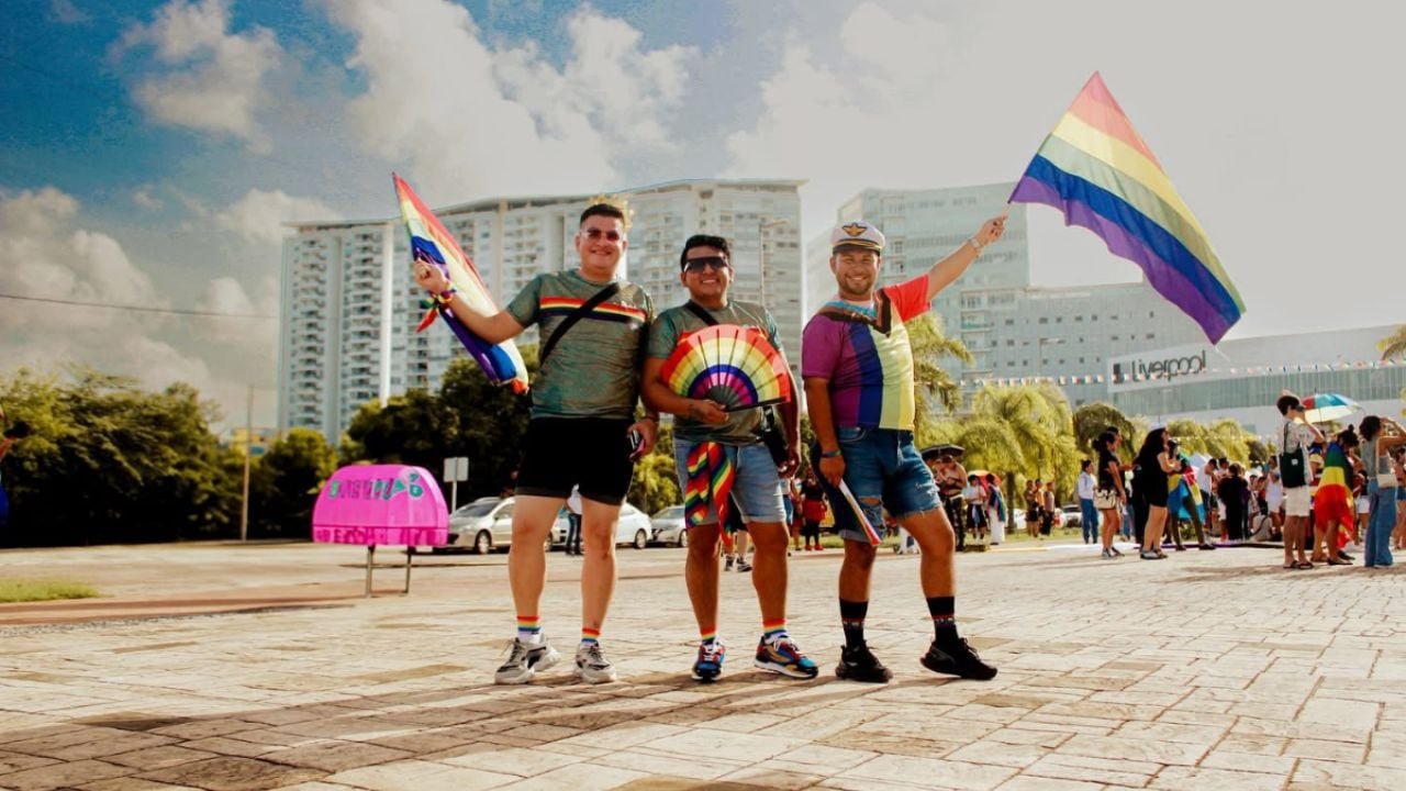 People at a Pride event in Cancún with rainbow flags