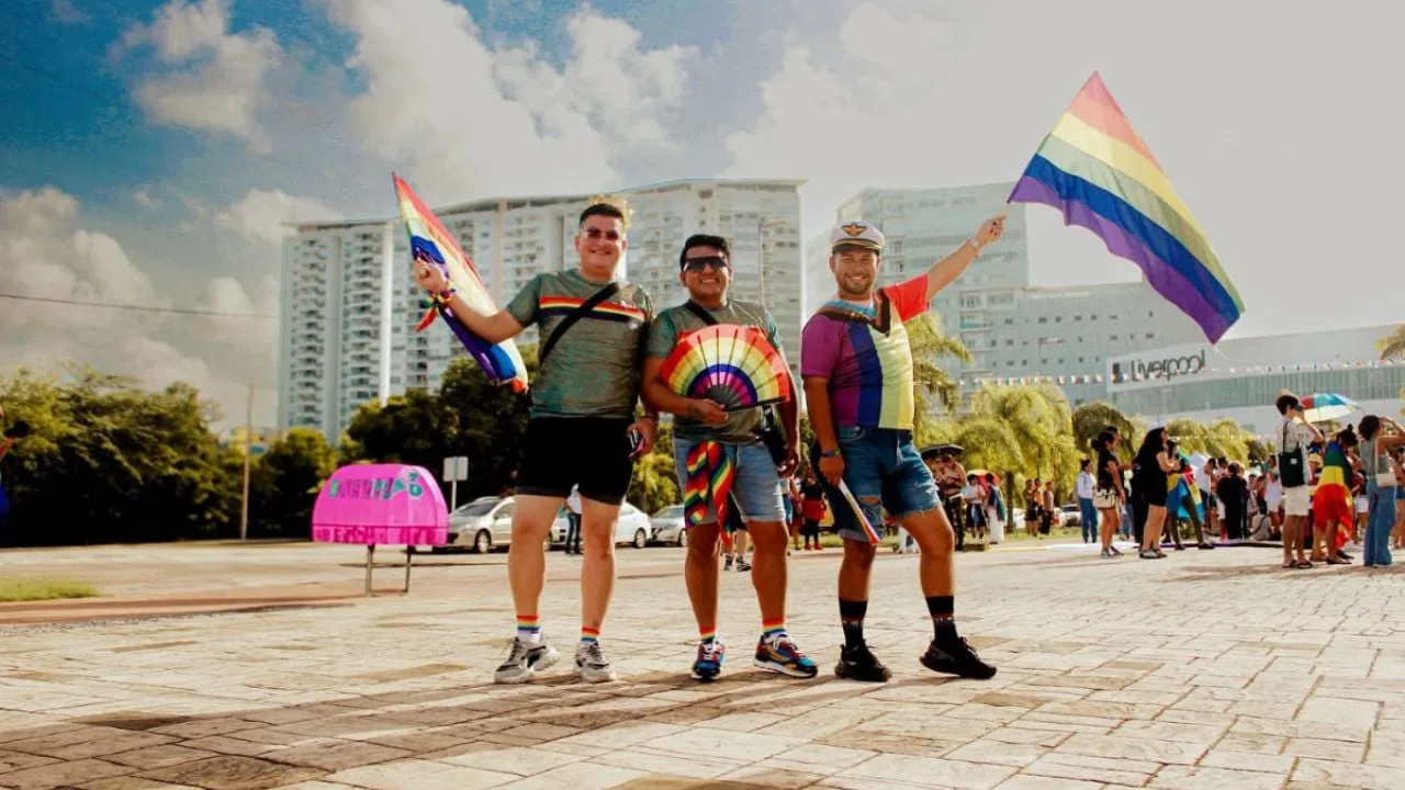 People at a Pride event in Cancún with rainbow flags