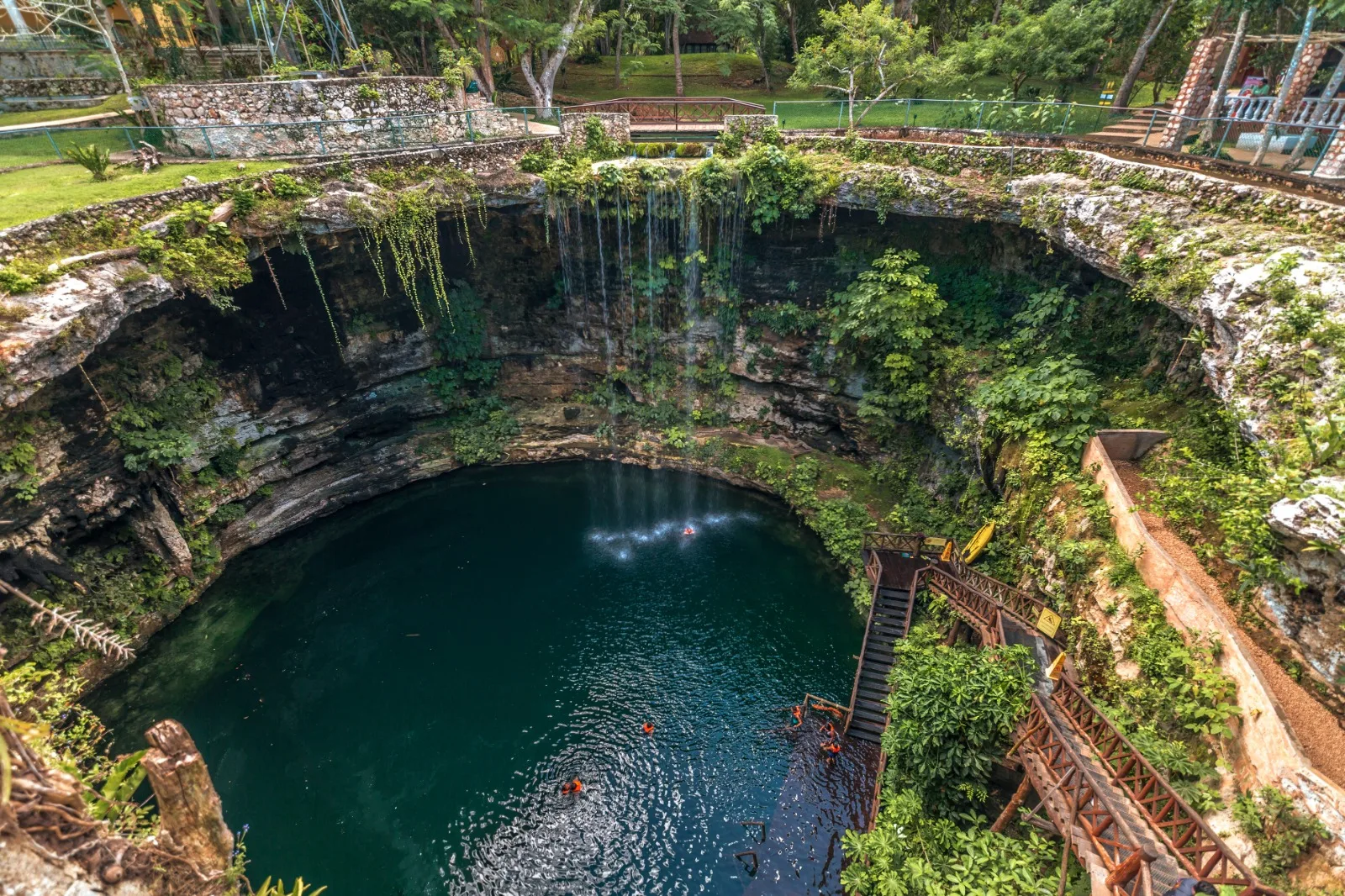 Turquoise waters of Cenote Saamal surrounded by rock formations and jungle vegetation at Selva Maya eco-park in Valladolid, Yucatan