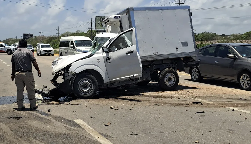 A white pickup truck with severe front-end damage after crashing into a metal pole on a highway