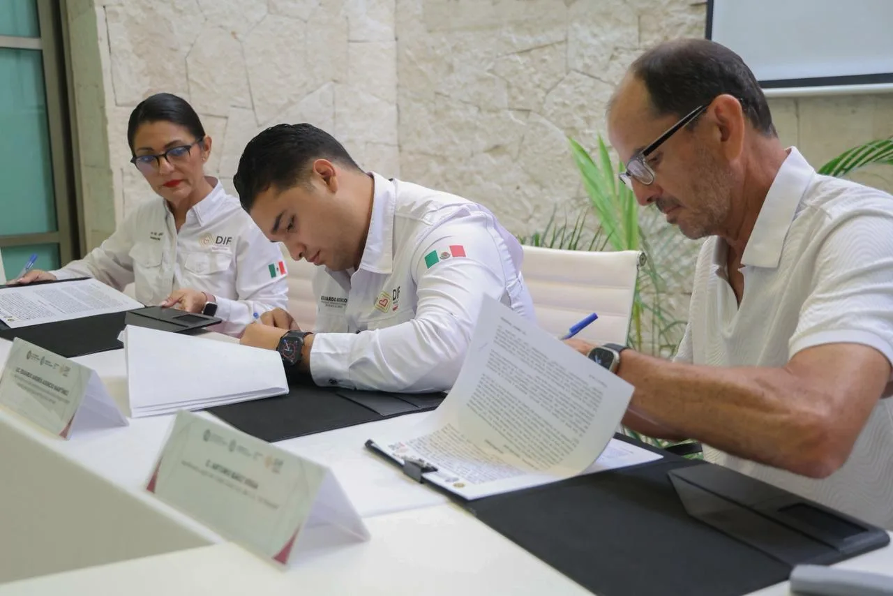 Officials from DIF Playa del Carmen and Ultramar sign a collaboration agreement at a desk.