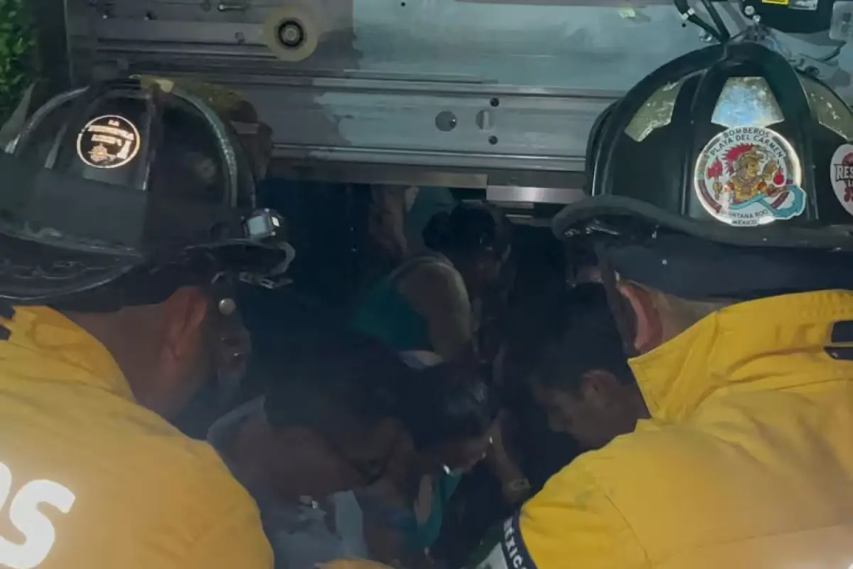 Emergency personnel working to open an elevator door during a rescue operation in Playa del Carmen