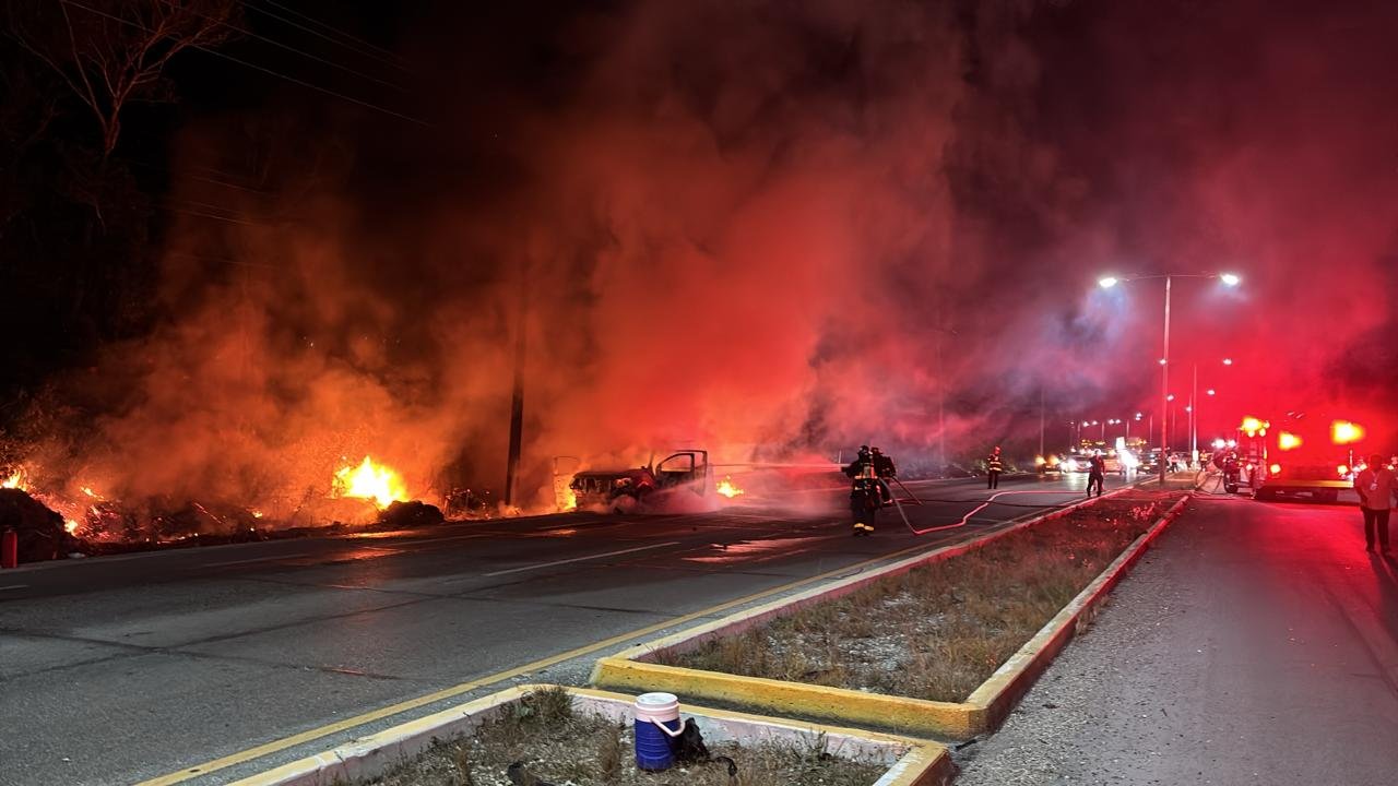 Firefighters extinguishing a burning vehicle that carried 300 liters of fuel on Highway 307 in Playa del Carmen