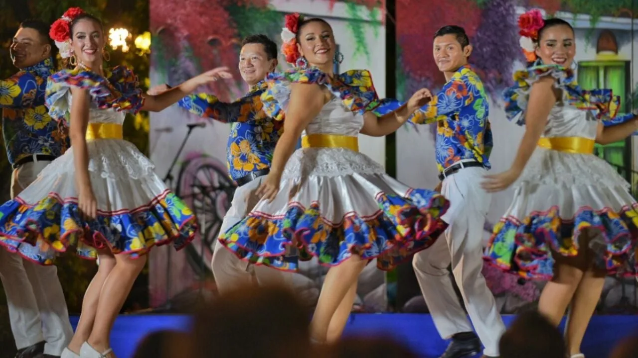 Folk dancers in colorful traditional costumes performing on stage at the Patrimonio Vivo festival in Chetumal