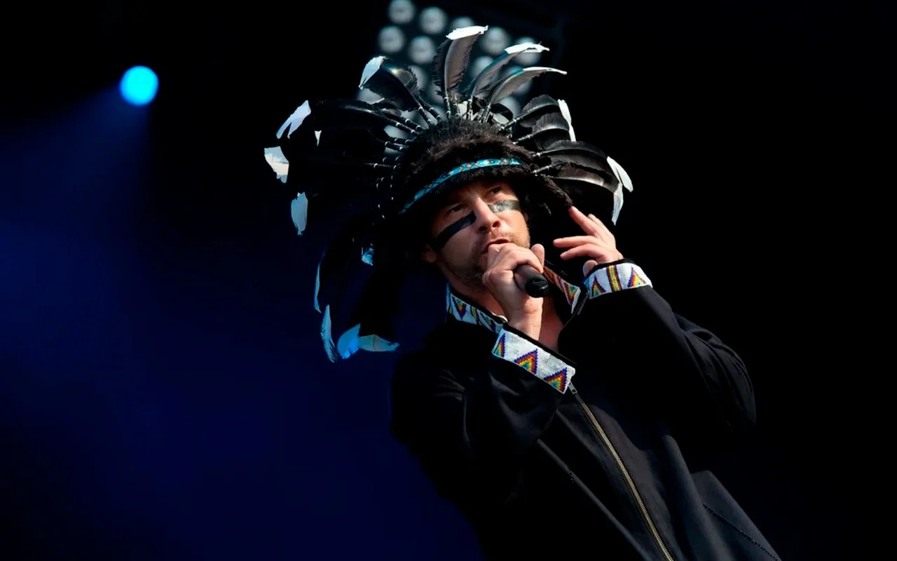 Jamiroquai performing live on stage with colorful lights
