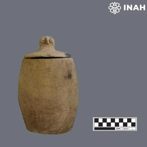 Restored Maya funerary urn with a lid shaped like an owl, displayed in a museum setting