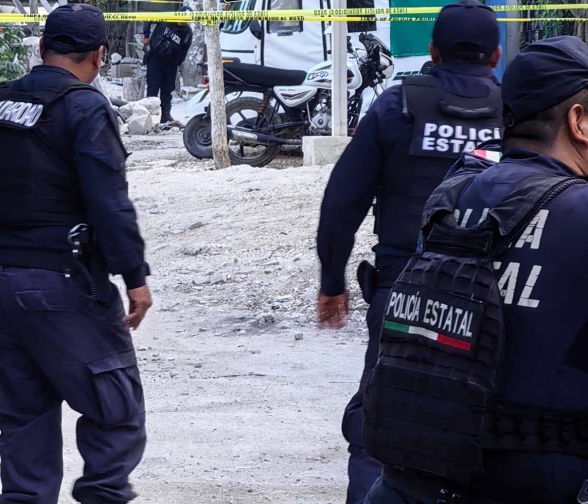 A mototaxi riddled with bullet holes parked on a street in Playa del Carmen, surrounded by police tape