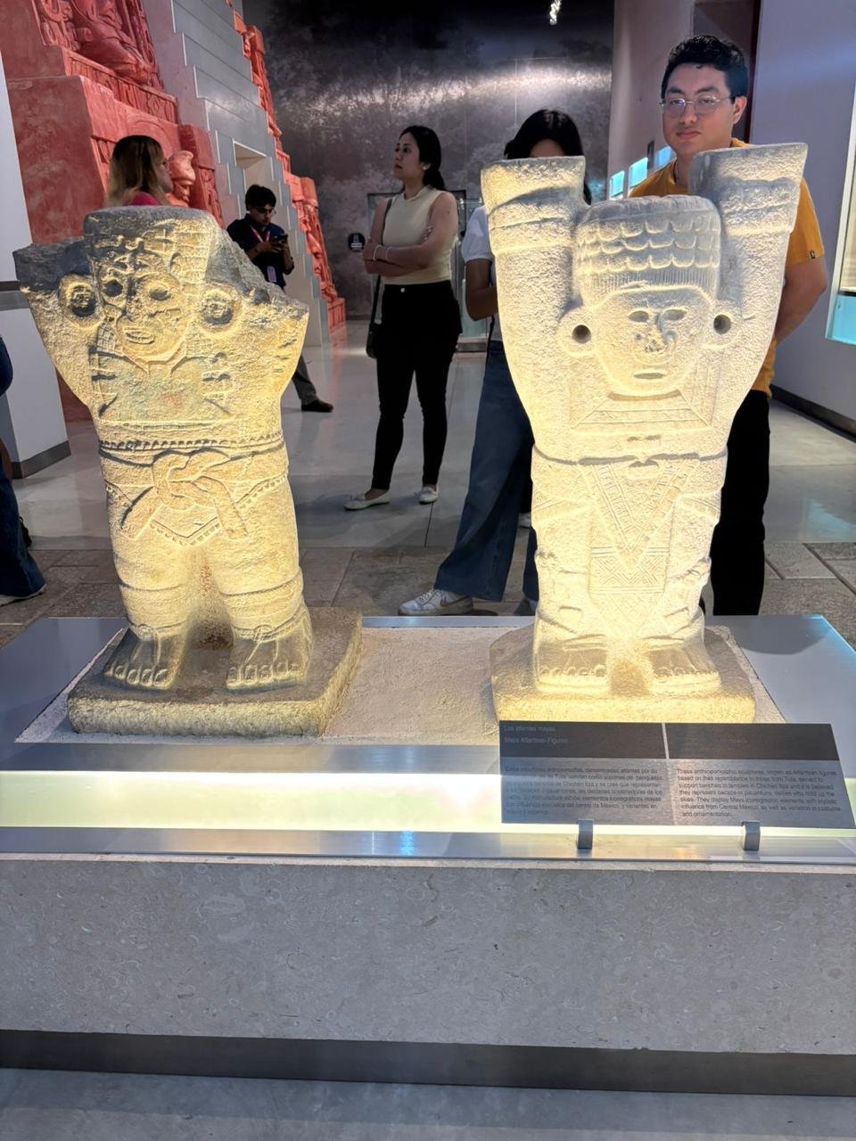 Visitors walking through a dimly lit museum hall with Maya artifacts during the Sembradores del Cielo night tour