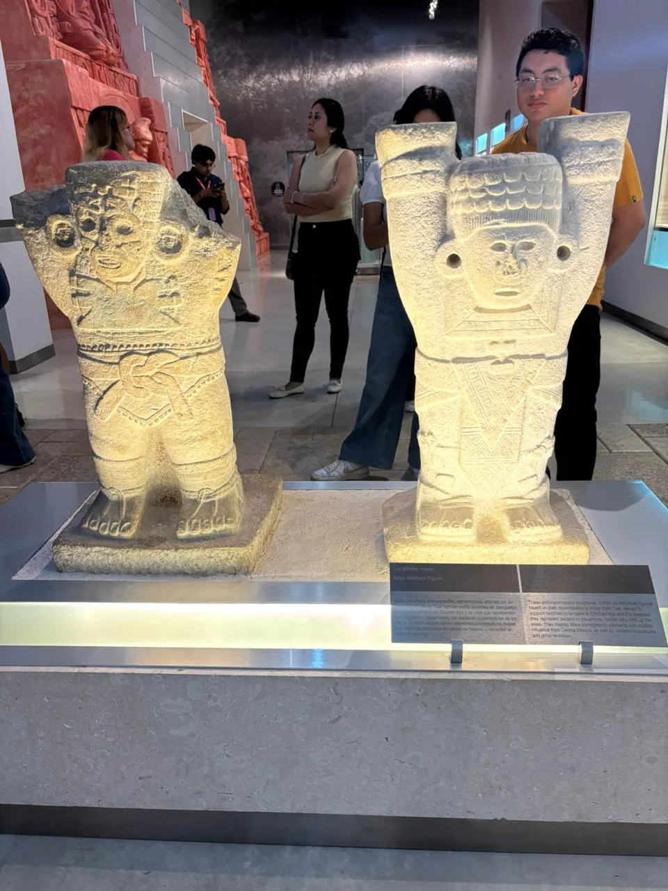 Visitors walking through a dimly lit museum hall with Maya artifacts during the Sembradores del Cielo night tour