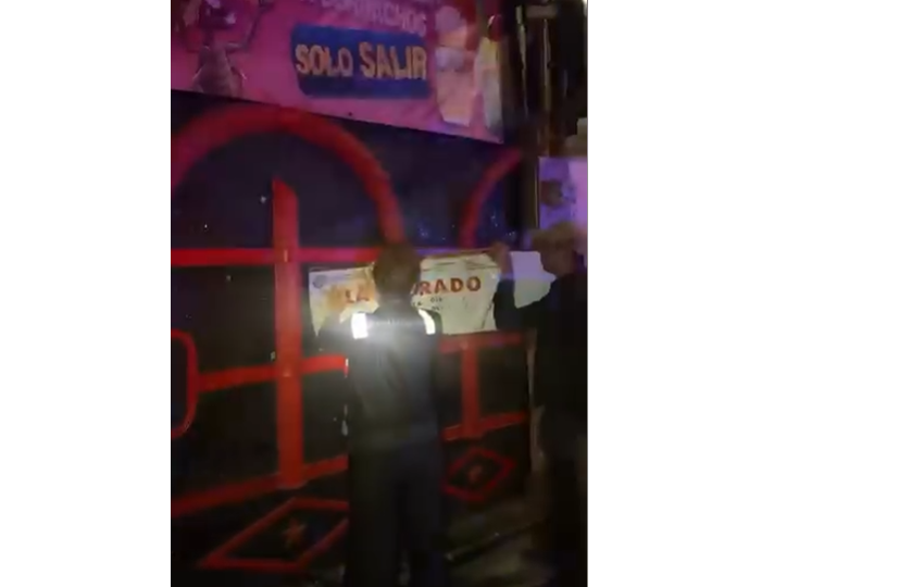 Municipal inspectors and police officers outside a closed bar in Playa del Carmen at night